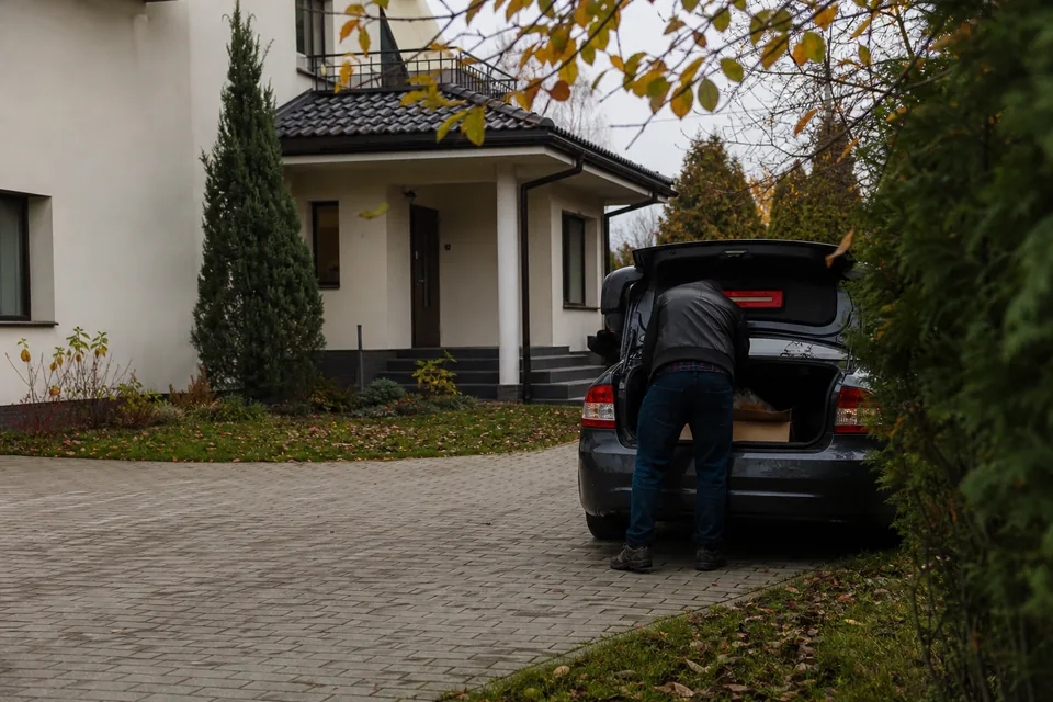 Dom jednorodzinny z ogrodem, przy podjeździe zaparkowany samochód